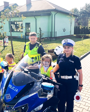 Dziecko na policyjnym motocyklu i dwójka policjantów przy nim