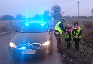 Policjantka przekazuje odblaski dzieciom