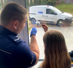 policjant pokazuje sposób zbierania śladów z szyby