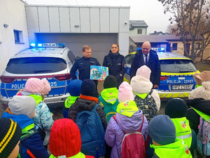 Grupa uczniów w odblaskach oraz policjanci i wójt