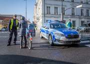 policjant podczas służby na ulicy oraz radiowóz i rowerzysta