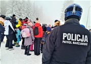 osoby na stoku i policjant w mundurze z napisem Patrol narciarski