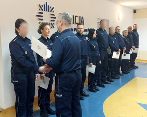 Grupa policjantów odbiera listy gratulacyjne od komendanta