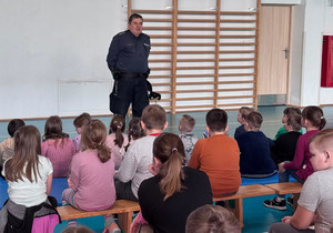 Policjant i grupa uczniów podczas zajęć w hali sportowej