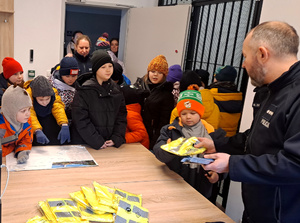 policjant rozdaje dzieciom elementy odblaskowe