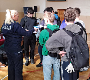 Policjantka rozdaje informatory uczestnikom targów