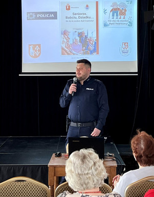 Policjant podczas spotkania z seniorami w sali Domu Kultury