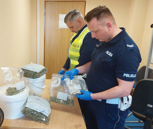 policjanci ruchu drogowego przy stole, na którym są opakowania z zabezpieczonymi narkotykami