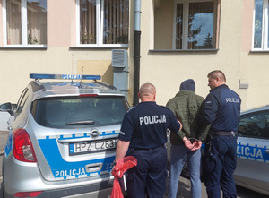 Policjanci prowadzą zatrzymanego do radiowozu