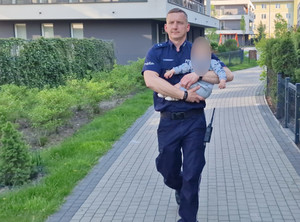 policjant niesie dziecko do radiowozu
