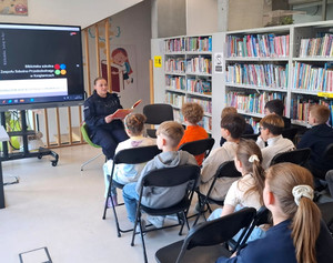 Policjantka czyta książkę grupie uczniów