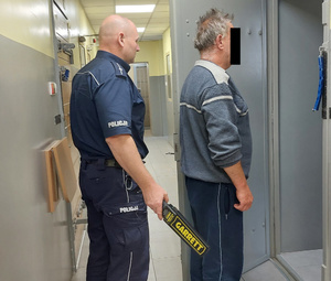 Policjant doprowadza zatrzymanego do celi