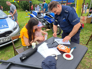 Policjant przy stanowisku pokazuje pracę technika kryminalistyki