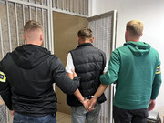 Policjanci wprowadzają zatrzymanego do celi