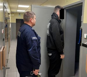 Policjant doprowadza zatrzymanego do celi