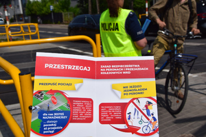 ulotka z radami , a w tle policjantka rozmawia z rowerzystą