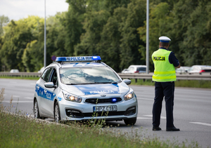 policjant przy radiowozie podczas służby na drodze