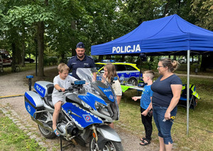 stanowisko policyjne z motocyklem i radiowozem podczas pikniku