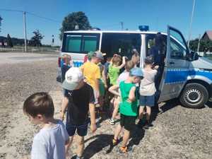 grupa chłopców i policjantka przy radiowozie