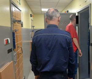 Policjant z jednym z zatrzymanych mężczyzn przed celą