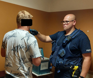Policjant przeprowadza badanie trzeźwości zatrzymanego mężczyzny
