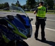 policjant drogówki prowadzi kontrole na ulicy, obok motocykl służbowy
