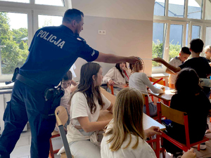 policjant wręcza odblaski uczestnikom spotkania
