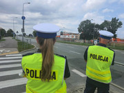 Dwoje policjantów w kamizelkach podczas służby na drodze