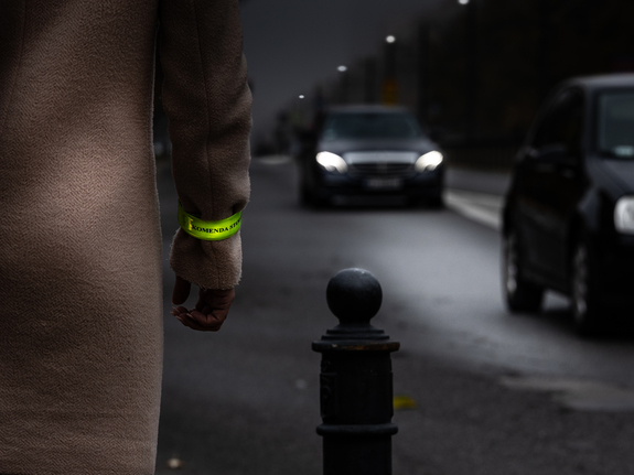 Osoba z opaską na rękawie na drodze po zmierzchu