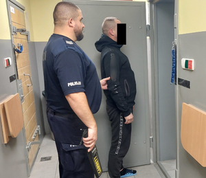 Policjant z zatrzymanym mężczyzną przed celą