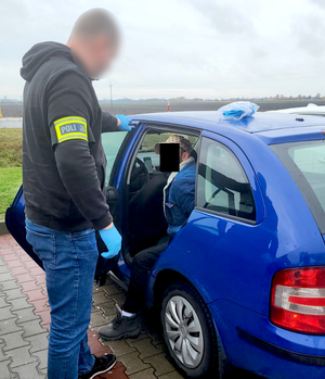 Policjant kryminalny zatrzymuje mężczyznę przy samochodzie