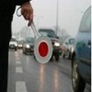 Reka policjanta z tarczą na tle jadących pojazdów