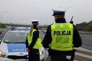 Policjanci przed radiowozem na drodze