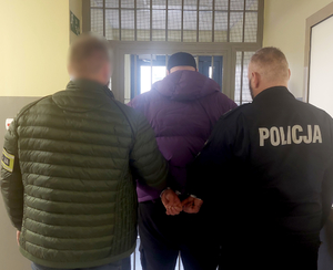 Policjanci z zatrzymanym przed wyjścim z pomieszczenia dla osób zatrzymanych