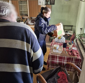 policjantka pomaga starszemu mężczyźnie przygotować posiłek