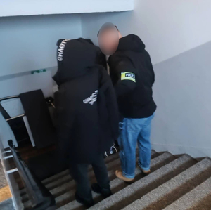 Zatrzymany mężczyzna prowadzony przez policjanta