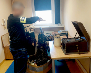 Policjant z zabezpieczonymi przedmiotami- lalki i zabytkowy sprzęt