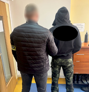 policjant kryminalny z zatrzymanym mężczyzną w pomieszczeniu