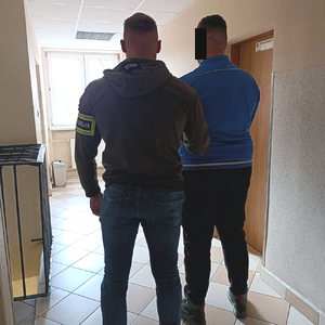 policjant kryminalny prowadzi zatrzymanego