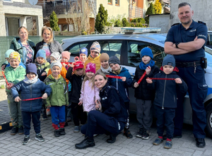 Policjanci z grupą dzieci na tle radiowozu