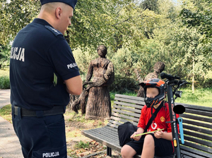 Policjant rozmawia z użytkownikiem hulajnogi w parku
