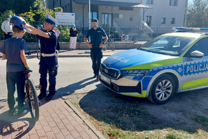 Policjanci wręczają kaski rowerzystom
