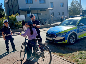 Policjanci wręczają kaski rowerzystom