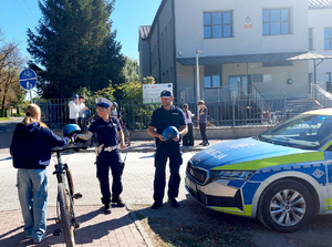 Policjanci wręczają kaski rowerzystom